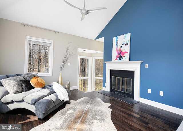 living area with ceiling fan, baseboards, wood finished floors, and a glass covered fireplace