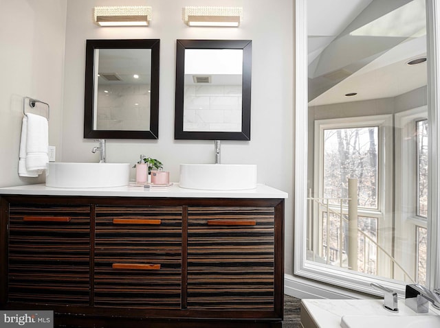 full bathroom with double vanity, visible vents, and a sink