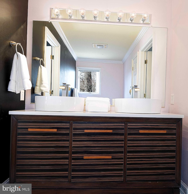 bathroom featuring visible vents, crown molding, and double vanity