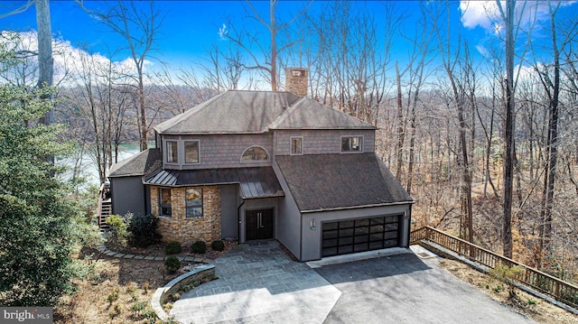 view of front of house featuring stairway, a standing seam roof, a chimney, aphalt driveway, and metal roof