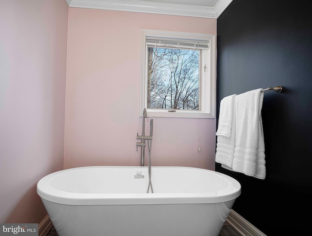 full bath featuring a freestanding bath, baseboards, and ornamental molding