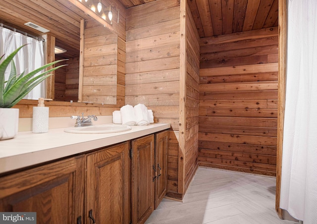 bathroom with wooden ceiling, wood walls, and vanity