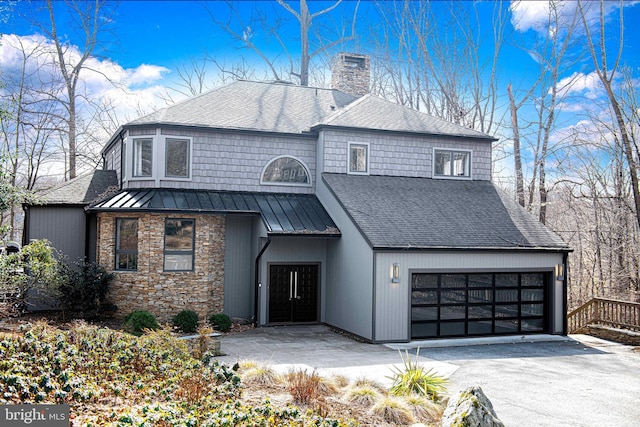 view of front of house featuring driveway, a standing seam roof, a chimney, a shingled roof, and metal roof