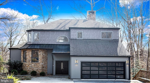 view of front of property featuring a standing seam roof, roof with shingles, an attached garage, metal roof, and a chimney