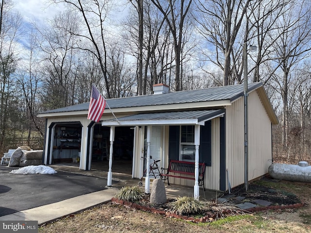 view of front of property with covered porch, metal roof, aphalt driveway, and a chimney