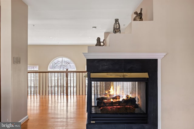 room details with wood finished floors and a multi sided fireplace