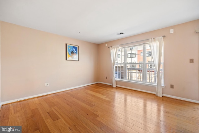 spare room featuring light wood-style floors, visible vents, and baseboards