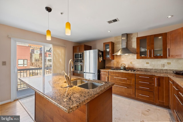 kitchen featuring wall chimney range hood, visible vents, appliances with stainless steel finishes, and backsplash