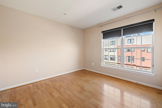 unfurnished room with light wood-style floors, baseboards, and visible vents