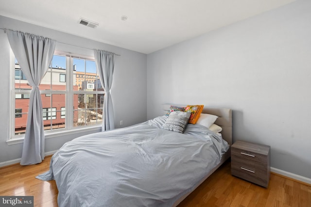 bedroom with baseboards, visible vents, and light wood-style floors