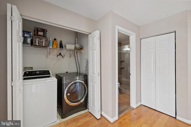 washroom featuring laundry area, independent washer and dryer, light wood-style flooring, and baseboards