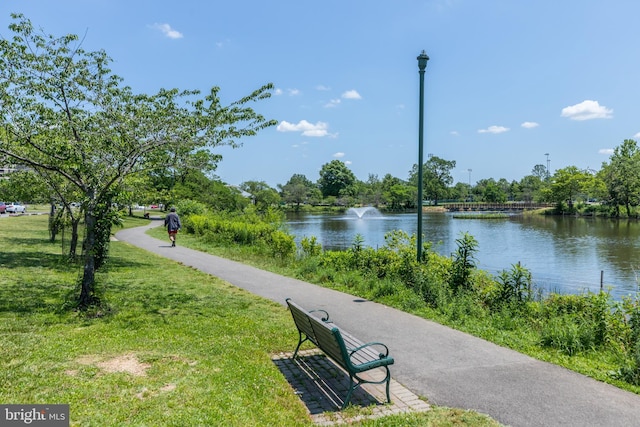 view of property's community with a water view and a lawn