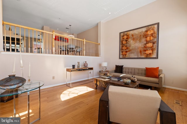 living room featuring visible vents, baseboards, and wood finished floors