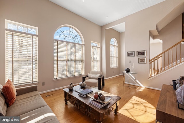 living room with stairs, hardwood / wood-style flooring, visible vents, and baseboards