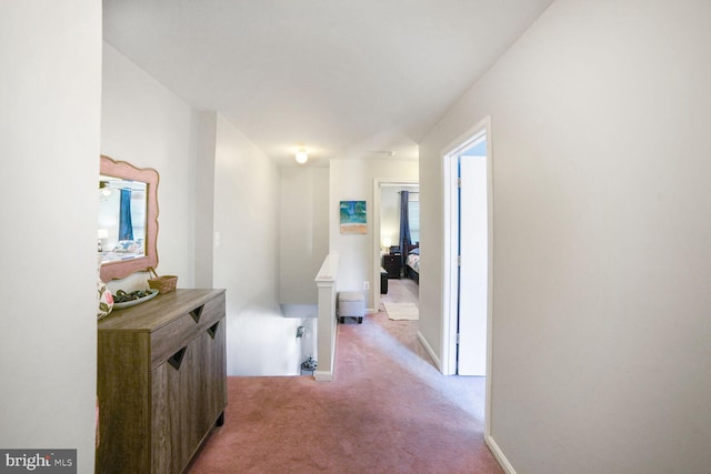 corridor with baseboards and light colored carpet