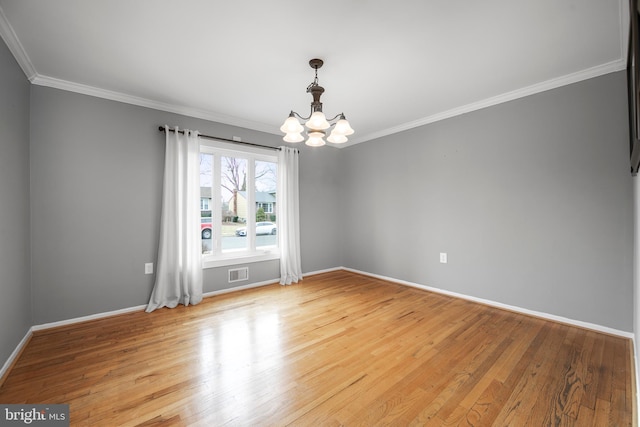 spare room with a chandelier, ornamental molding, light wood-type flooring, and visible vents