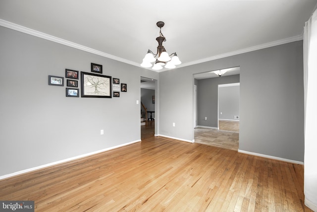 unfurnished room with a chandelier, ornamental molding, light wood-style flooring, and baseboards