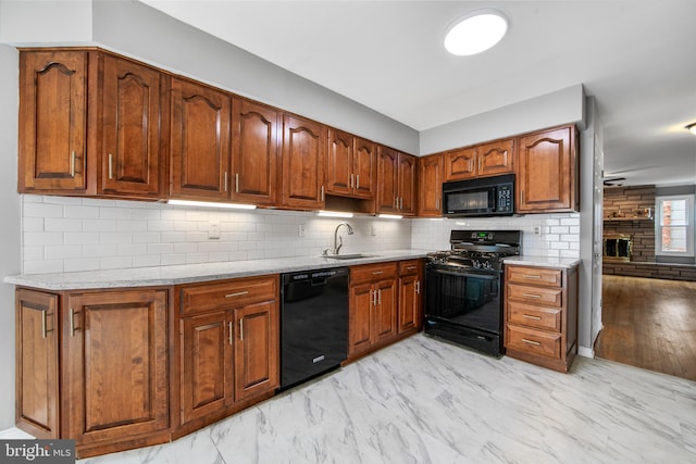 kitchen featuring marble finish floor, brown cabinets, decorative backsplash, a sink, and black appliances