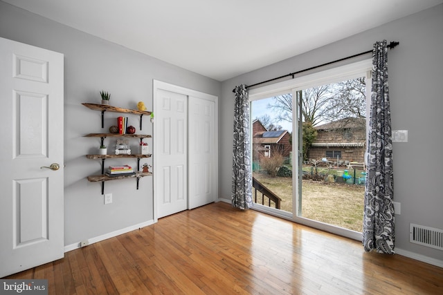 interior space featuring hardwood / wood-style flooring, visible vents, and baseboards