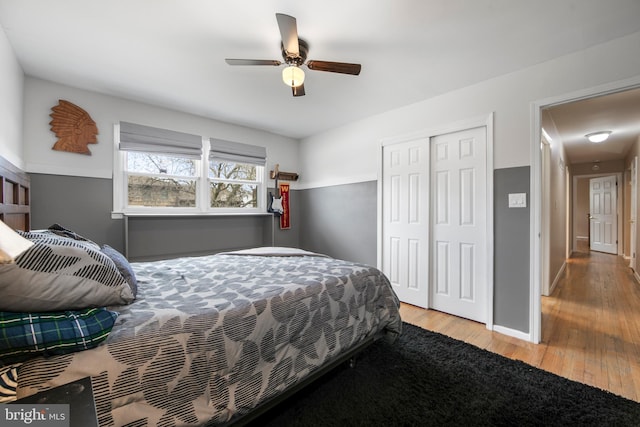 bedroom featuring ceiling fan, baseboards, a closet, and wood finished floors