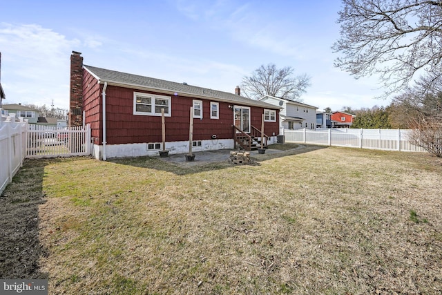 rear view of property with entry steps, a chimney, a fenced backyard, and a lawn