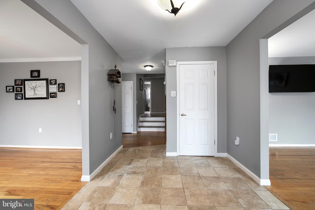 hallway with light wood-type flooring, stairs, and baseboards