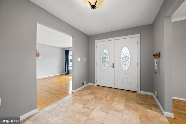 foyer entrance featuring visible vents, light wood-style flooring, and baseboards