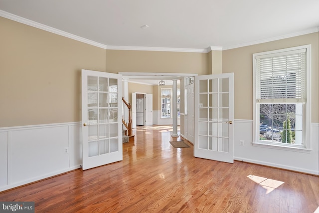 unfurnished room featuring french doors, a wainscoted wall, crown molding, stairway, and wood finished floors