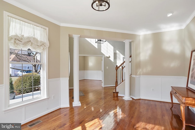 foyer featuring a wainscoted wall, decorative columns, visible vents, and wood finished floors