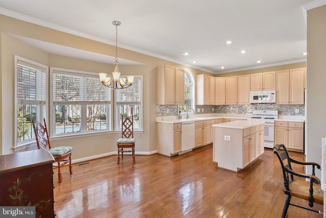 kitchen with light countertops, light brown cabinets, a sink, wood finished floors, and white appliances