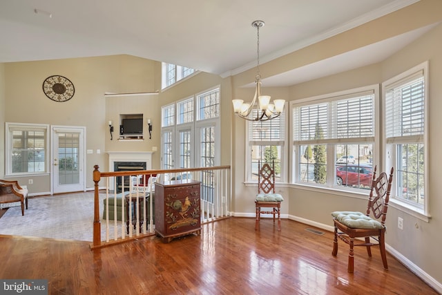 living area featuring baseboards, visible vents, wood finished floors, a fireplace, and a chandelier