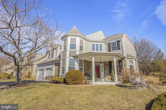 view of front of property featuring stone siding, a garage, and a front lawn