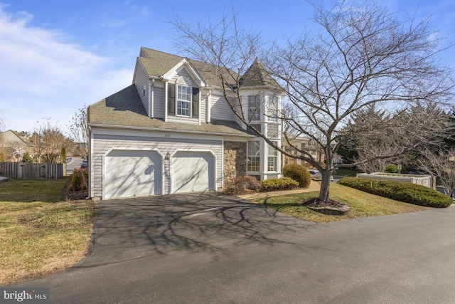 view of front facade with driveway, an attached garage, fence, and a front yard