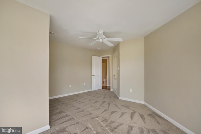 carpeted spare room featuring ceiling fan and baseboards