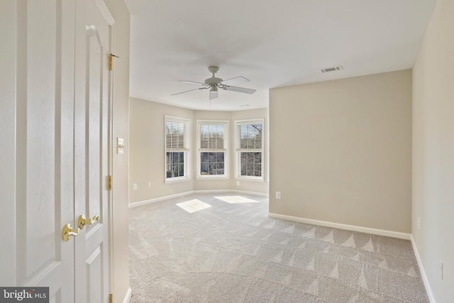 carpeted empty room featuring a ceiling fan, visible vents, and baseboards