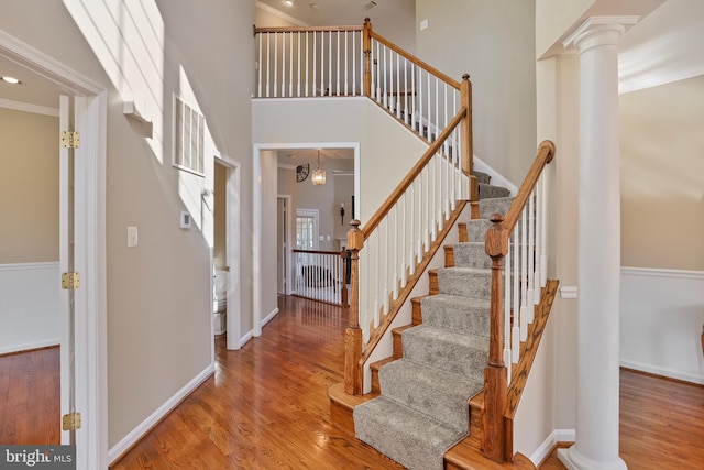 foyer featuring decorative columns, a high ceiling, and wood finished floors