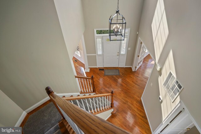 foyer entrance featuring a high ceiling, an inviting chandelier, wood finished floors, and baseboards