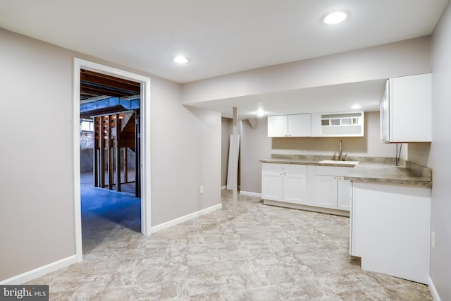 kitchen with baseboards, recessed lighting, a sink, and white cabinets