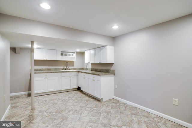 kitchen with baseboards, white cabinetry, a sink, and recessed lighting