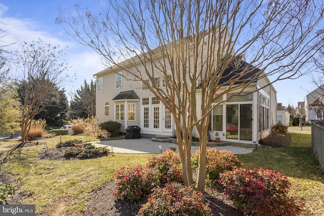 rear view of property with a patio, fence, a sunroom, a yard, and french doors