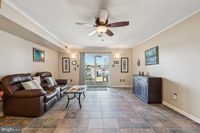 living area featuring ceiling fan, crown molding, baseboards, and dark tile patterned flooring