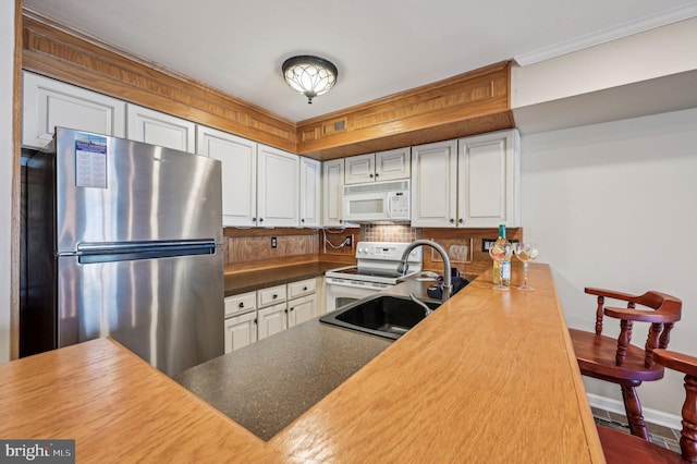 kitchen featuring backsplash, white cabinets, white appliances, and a sink