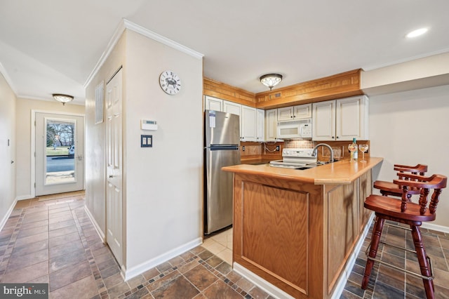 kitchen featuring white appliances, a peninsula, ornamental molding, light countertops, and tasteful backsplash