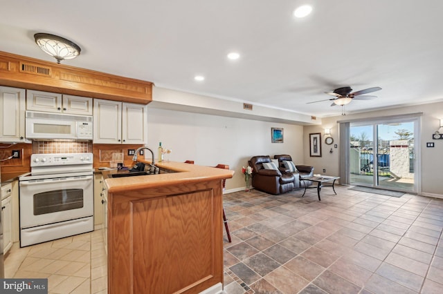 kitchen with tasteful backsplash, visible vents, open floor plan, a peninsula, and white appliances