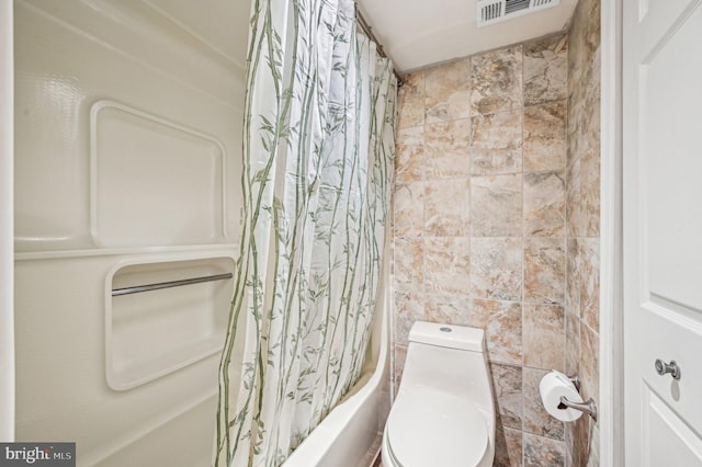 bathroom featuring visible vents, toilet, shower / bath combo with shower curtain, and tile walls