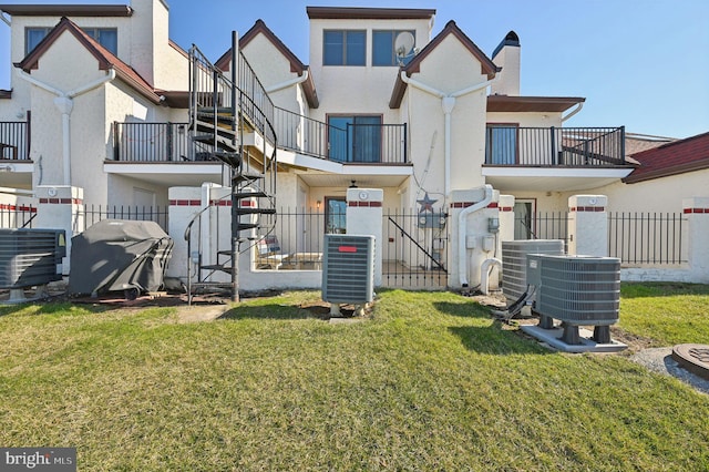 rear view of house with central air condition unit, a lawn, stucco siding, and fence