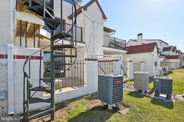 view of side of home with central AC unit, fence, and stucco siding