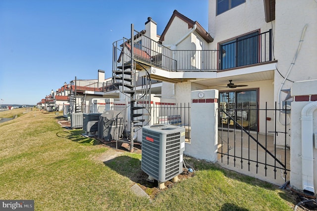 exterior space featuring central air condition unit, stucco siding, a lawn, and fence