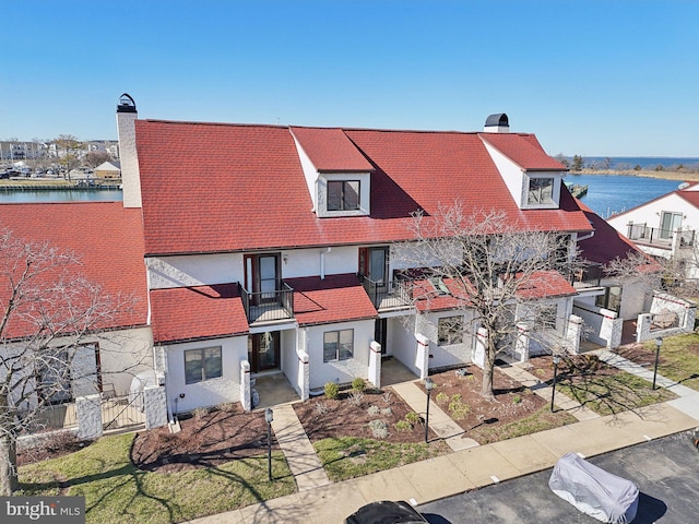 multi unit property with a chimney, a balcony, and a water view