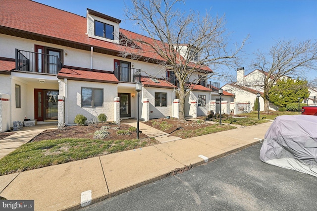 townhome / multi-family property with a balcony and a shingled roof